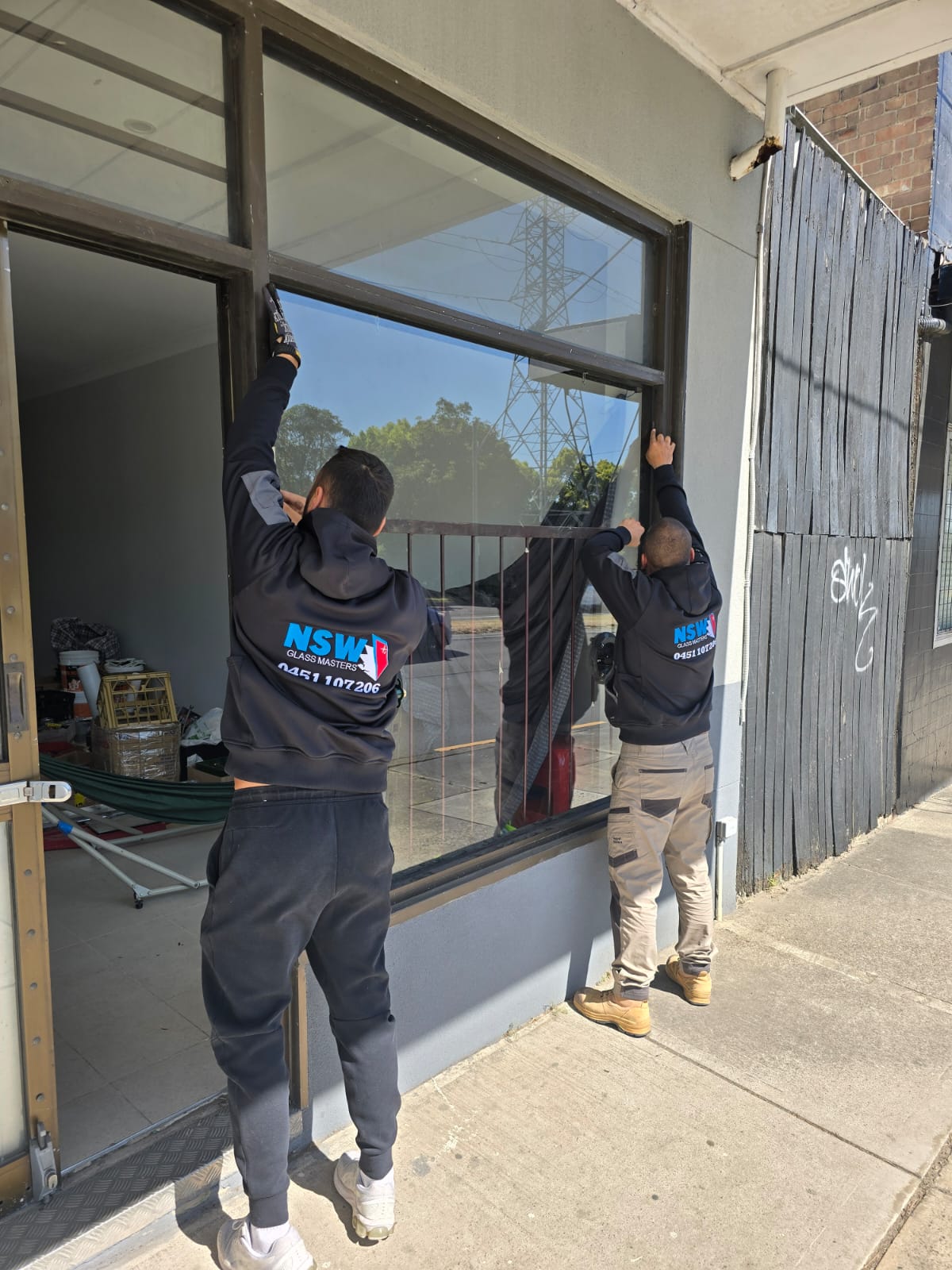 two nsw glass tradesmen installing a shop front glass panel